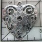 Decoración de metal plateada. Colgante corazón grabado con volutas.  3 x 3 cm. Fabscraps