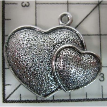 Decoración de metal plateada. Colgante con dos corazones superpuestos. 2,5 x 3 cm. Fabscraps
