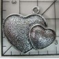 Decoración de metal plateada. Colgante con dos corazones superpuestos. 2,5 x 3 cm. Fabscraps