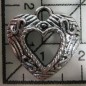 Decoración de metal plateada. Colgante corazón tallado, con centro vacio. 2 x 2 cm. Fabscraps
